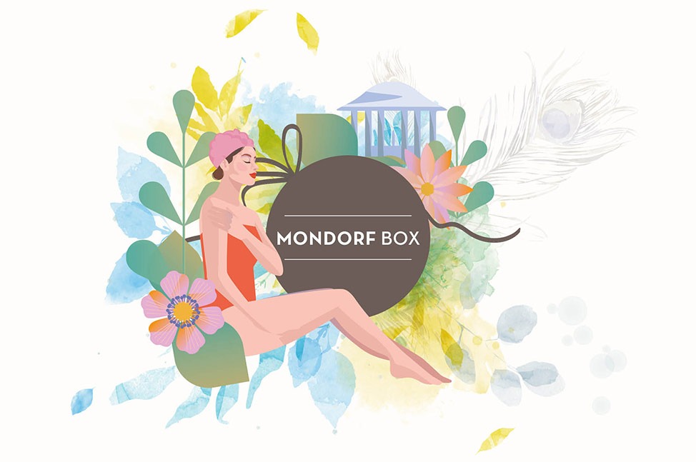 Un cercle brun avec le texte "MONDORF BOX" en blanc au centre, entouré de motifs floraux en aquarelle dans différentes nuances de bleu, jaune, gris, créant une sensation douce et élégante. Un ruban brun s'ajoute subtilement à la composition.
